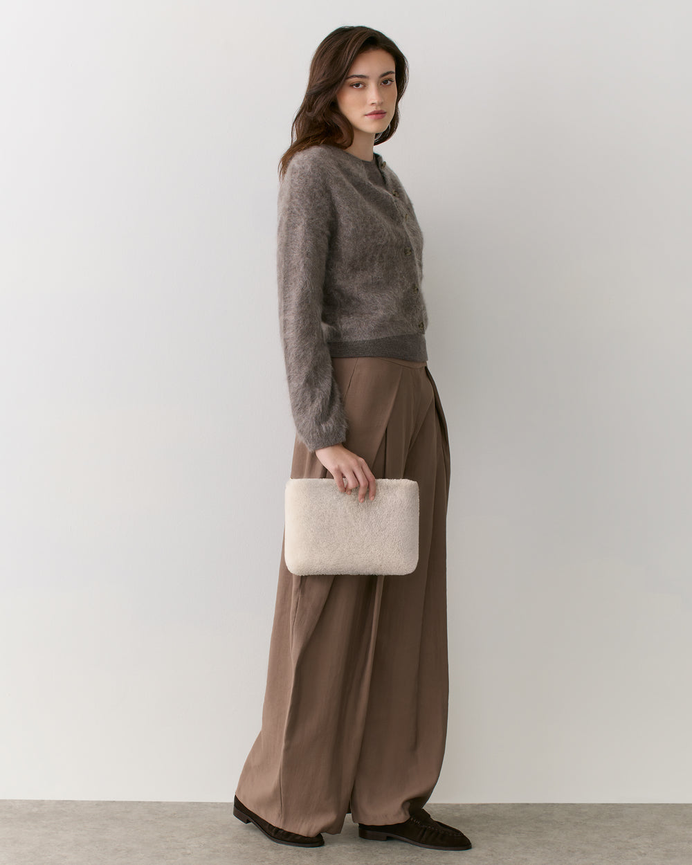Person wearing a sweater and wide-leg pants holding a clutch.