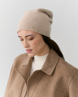 Person wearing a beanie and coat looking downward.