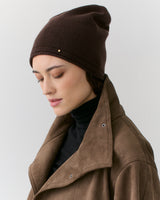Woman wearing beanie and jacket with eyes closed in profile view