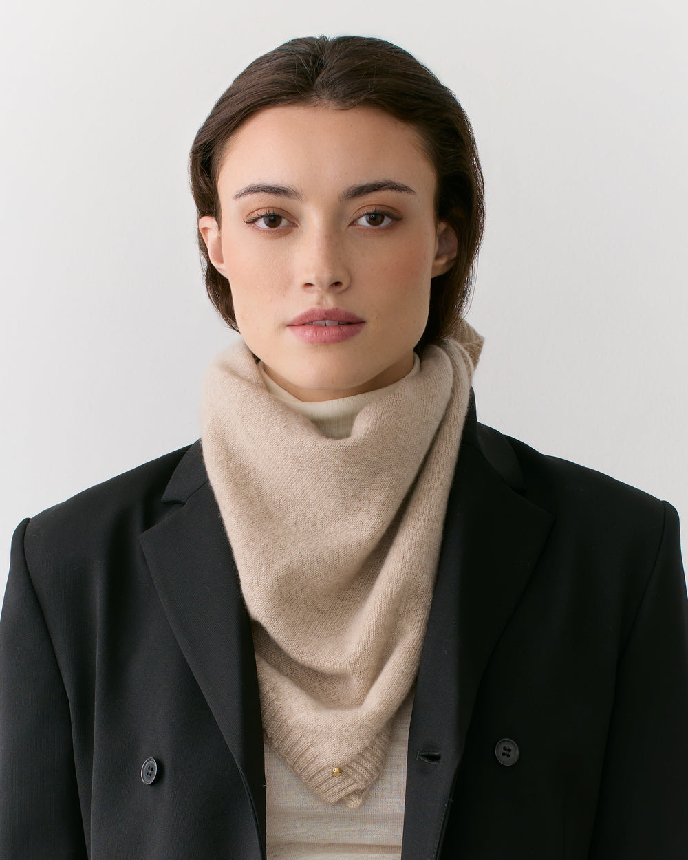 Person wearing a blazer and scarf looking at the camera