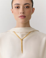 Person wearing a top with a necklace and earrings.