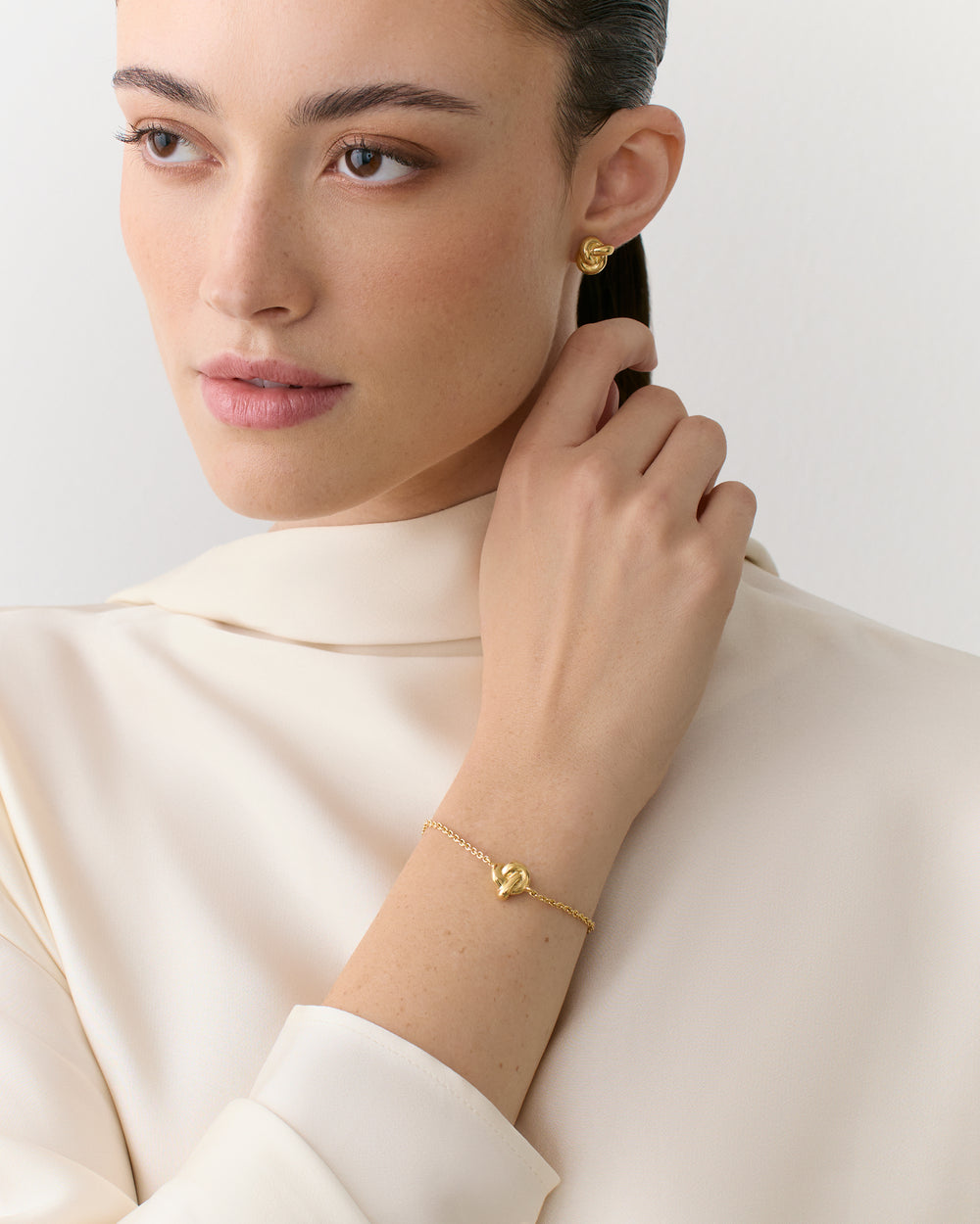 Person wearing earrings and bracelet, looking to the side.