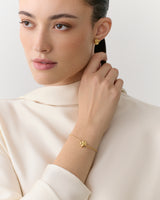 Person wearing earrings and bracelet, looking to the side.