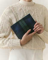 Person holding a plaid clutch wearing a textured sweater