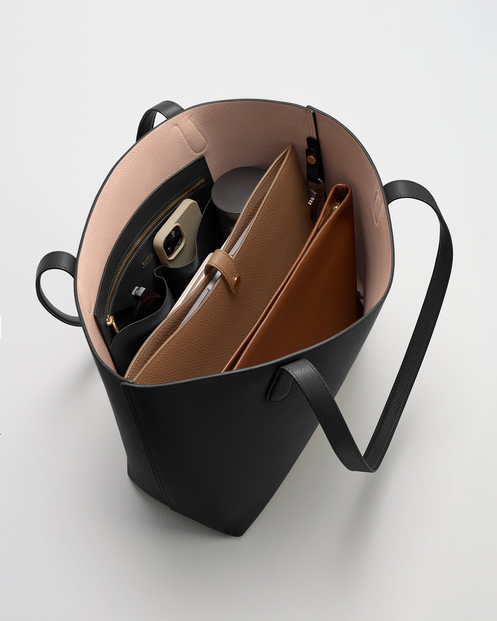 Open tote bag with pouches, wallet, and travel mug inside