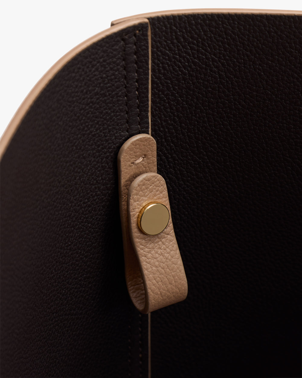 Close-up of a bag interior with a leather strap and metal button.