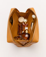 Open toiletry bag with bottles, a brush, and a small container inside.