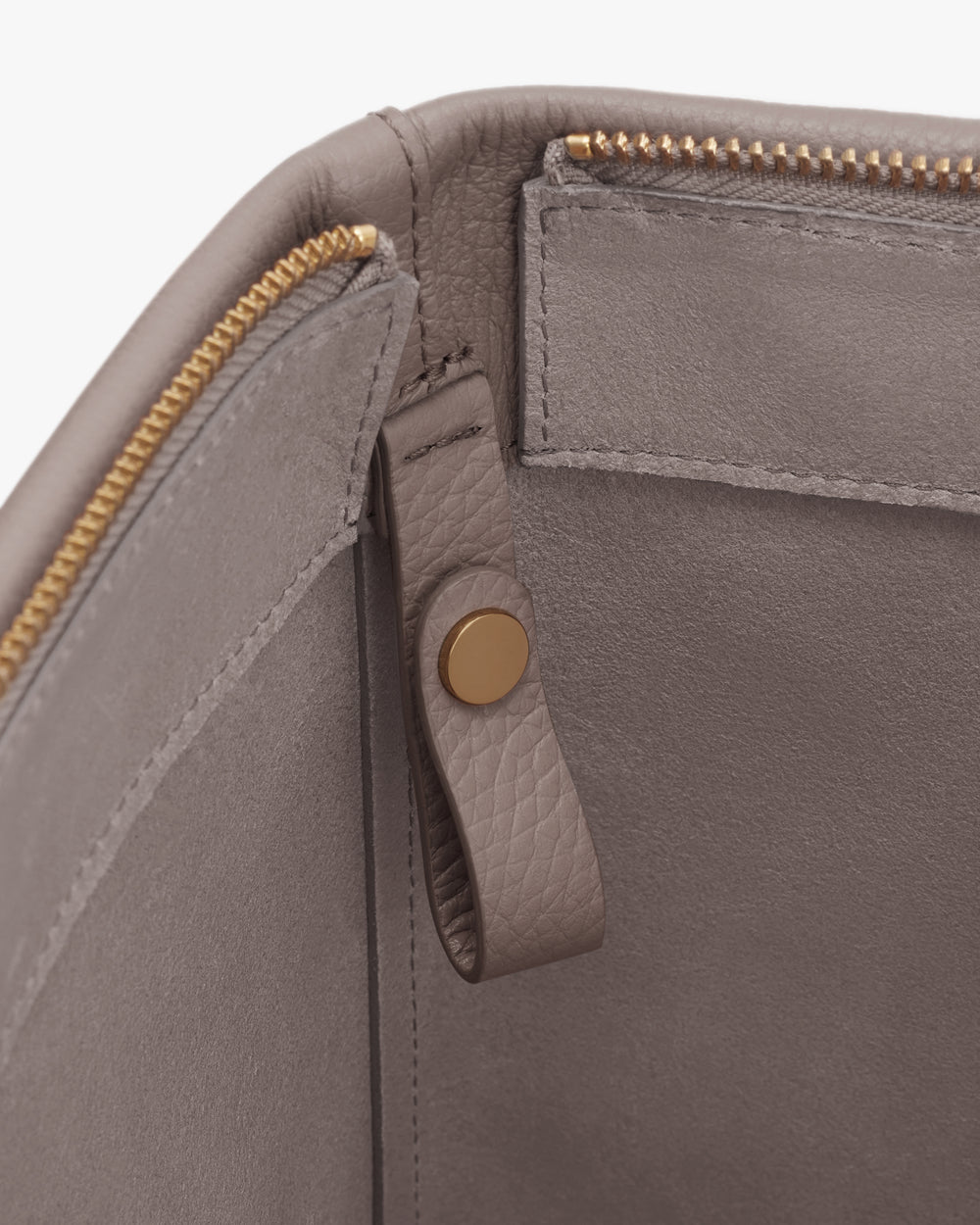 Close-up of a zippered bag with leather interior and snap button loop.