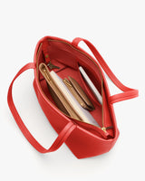 Open tote bag with items like a notebook, pencil case, and accessories inside.