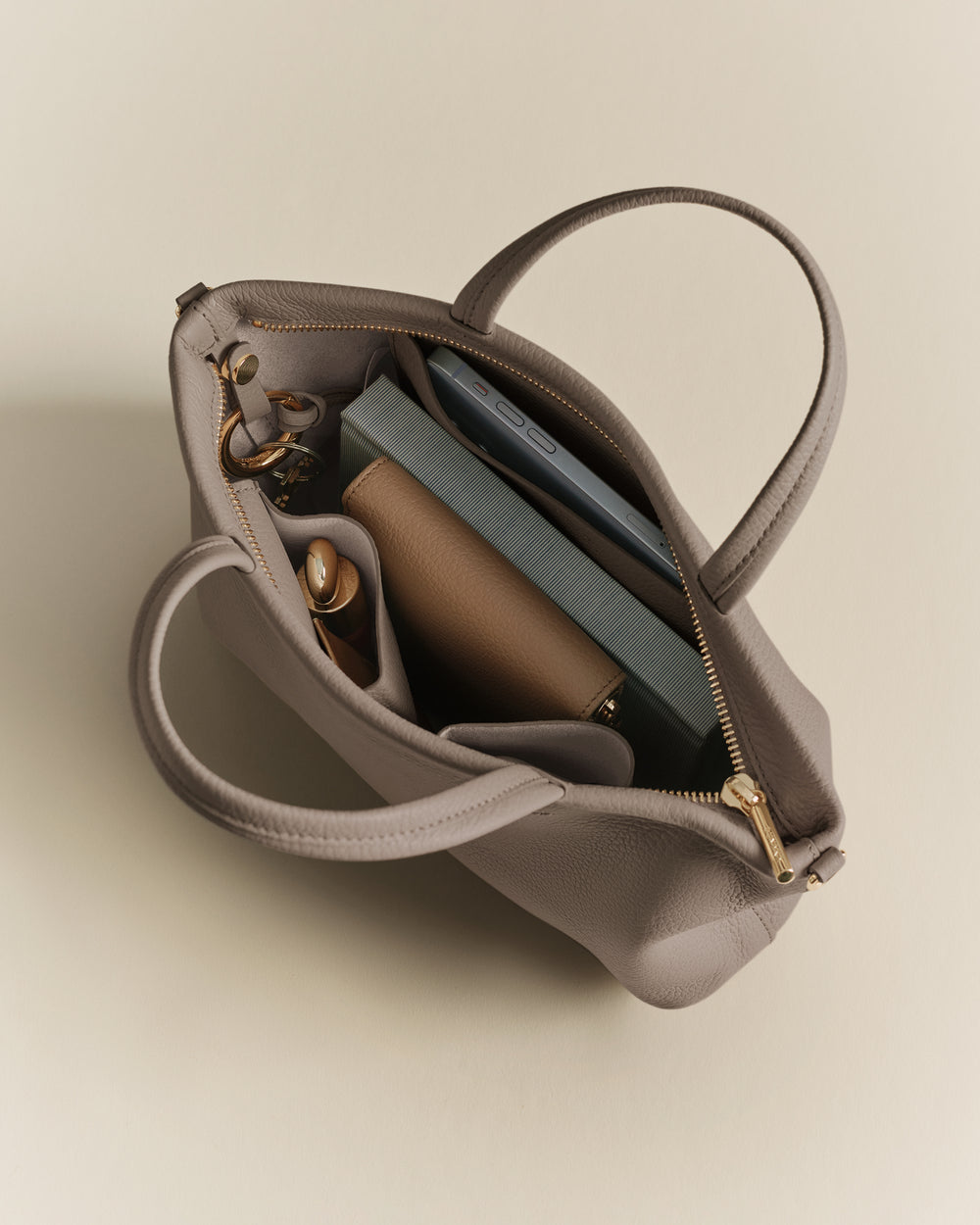 Open handbag with books, wallet, sunglasses, and bottle inside.