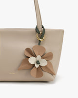 Handbag with a decorative flower attached to the strap.