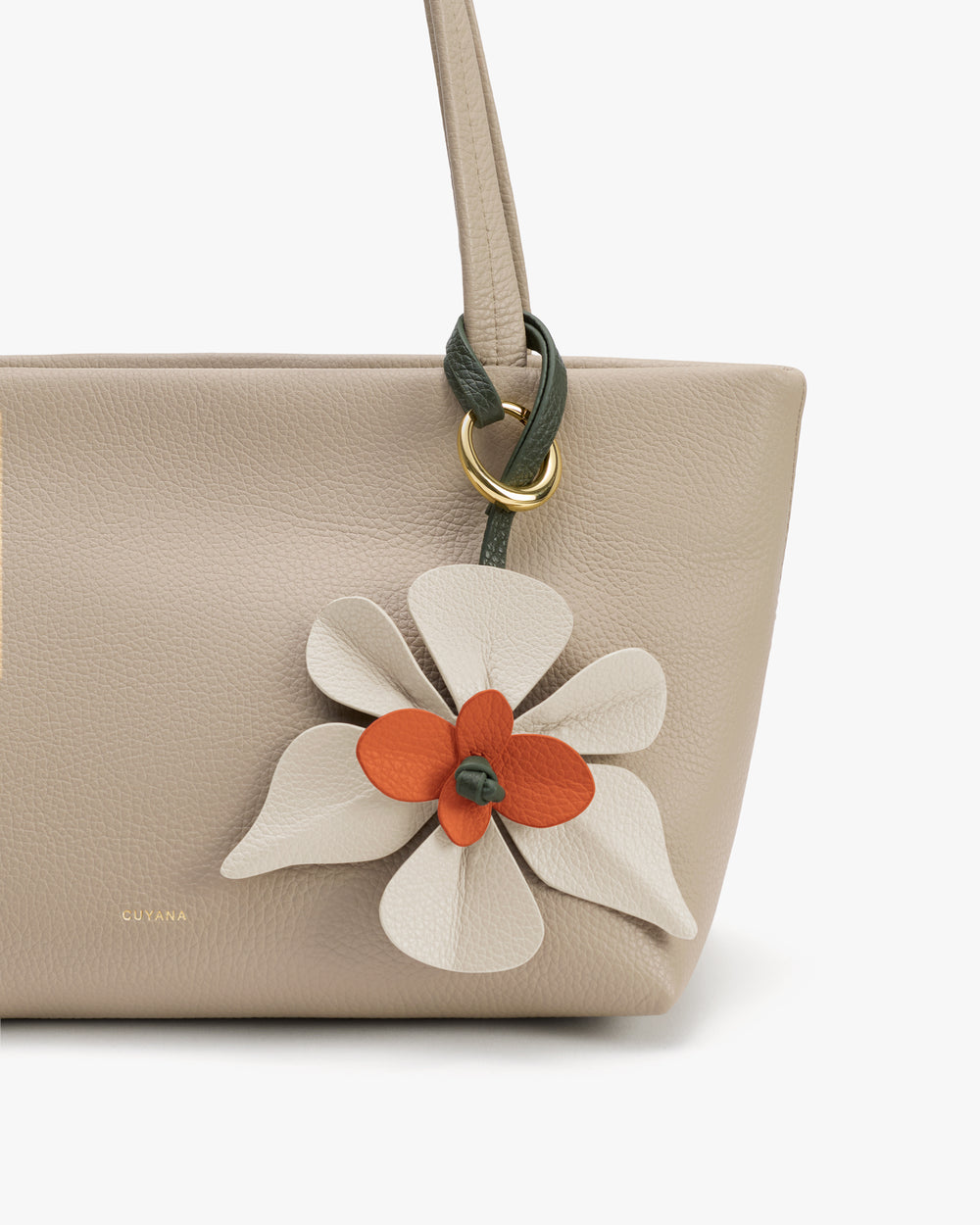 Handbag with a floral charm attached near the handle.