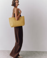 Person in long dress holding a tote bag.