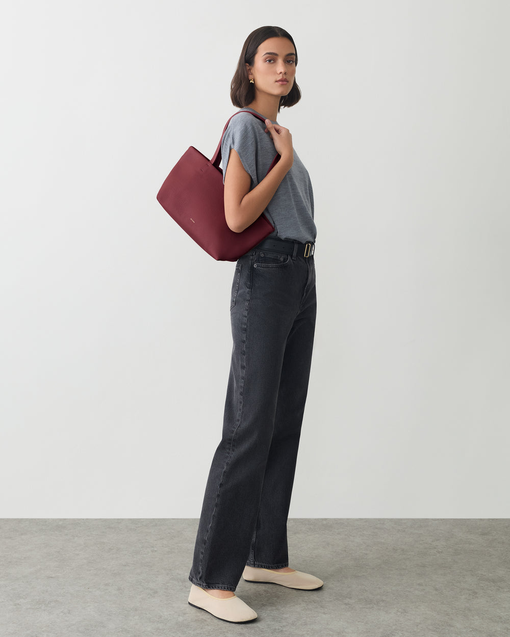 Person standing with a shoulder bag, wearing a t-shirt and jeans.