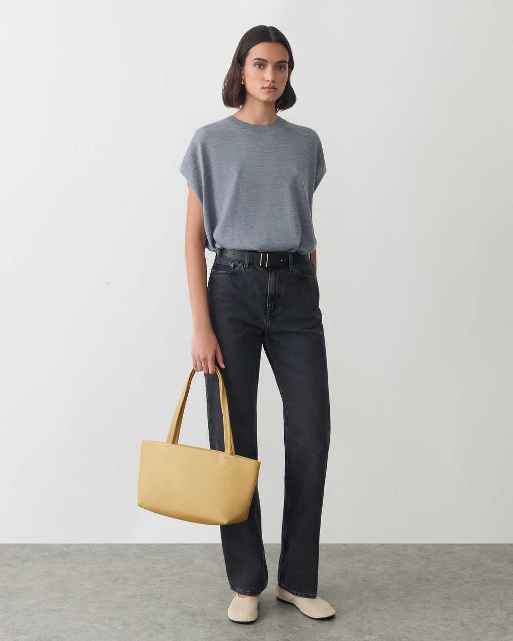 Person in a t-shirt and jeans holding a handbag.