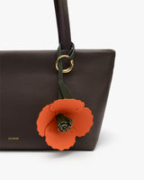 Handbag with an attached flower charm.