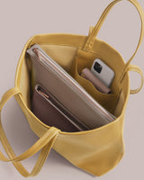 Open tote bag with a phone, two zippered pouches, and lipstick inside.