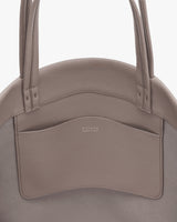 Round bag with two handles and front pocket.