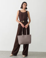 Person in a sleeveless top and pants holding a bag.