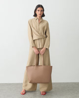 Person holding a large tote bag, wearing a coordinated outfit and sandals.