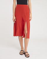 Person wearing a sleeveless top, midi skirt with slit, and sandals.