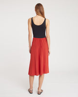 Person wearing a sleeveless top and midi skirt, standing with back turned.