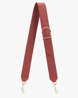 Bag strap with gold clasps and adjustable buckle lying flat.