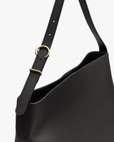 Shoulder bag with adjustable strap and metal ring detail.