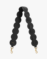 Bag strap with circular segments and gold clasps.