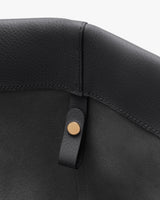 Close-up of a leather corner with a small strap and button detail.