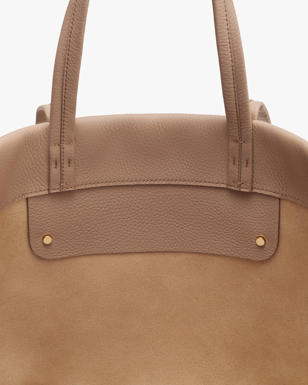 Close-up of a handbag with two handles and small metal studs.