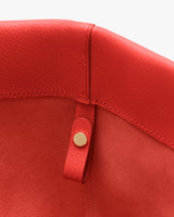 Close-up of a textured leather item with a circular metal snap button.