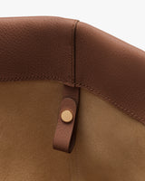 Close-up of inside corner of a leather bag with a button detail.