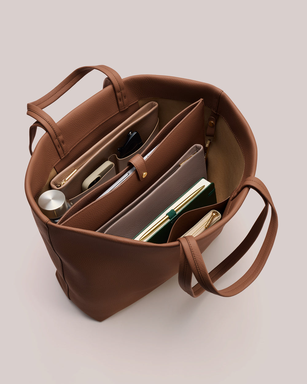 Open tote bag with organized items inside, including a notebook, phone, and water bottle.