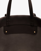 Close-up of handbag with two handles and stud details.