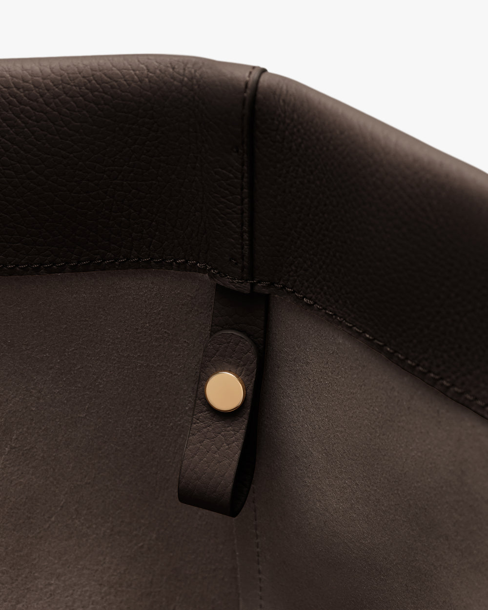 Close-up of a seam and button detail on a leather item.