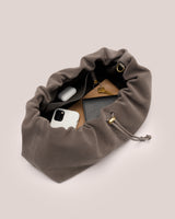 Open drawstring bag with phone, earbuds, keychain, and wallet inside.