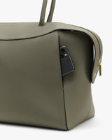 Travel bag with a phone in the side pocket, zipper visible.