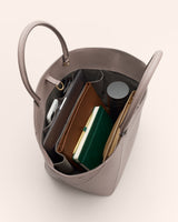 Open handbag with a notebook, tablet, and various items inside.
