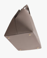 A handbag with four gold-tone studs on the bottom.