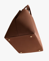 Angular handbag with bottom metal studs and top handles visible.