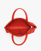 Handbag with open zipper and two handles, showing pockets inside.