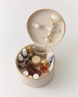 Round open case with skincare bottles and a facial roller inside.
