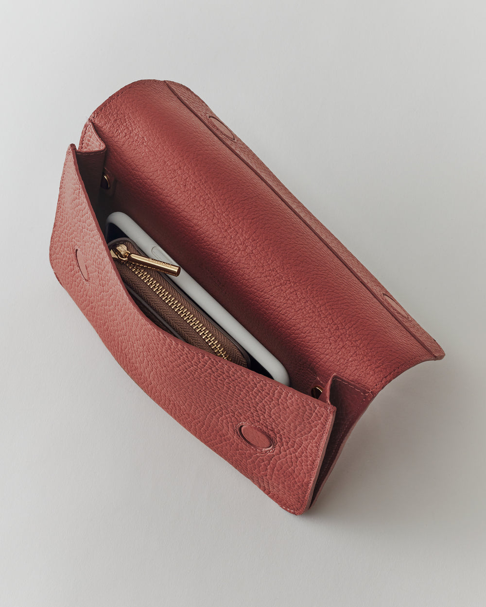 Open clutch with phone and wallet inside.