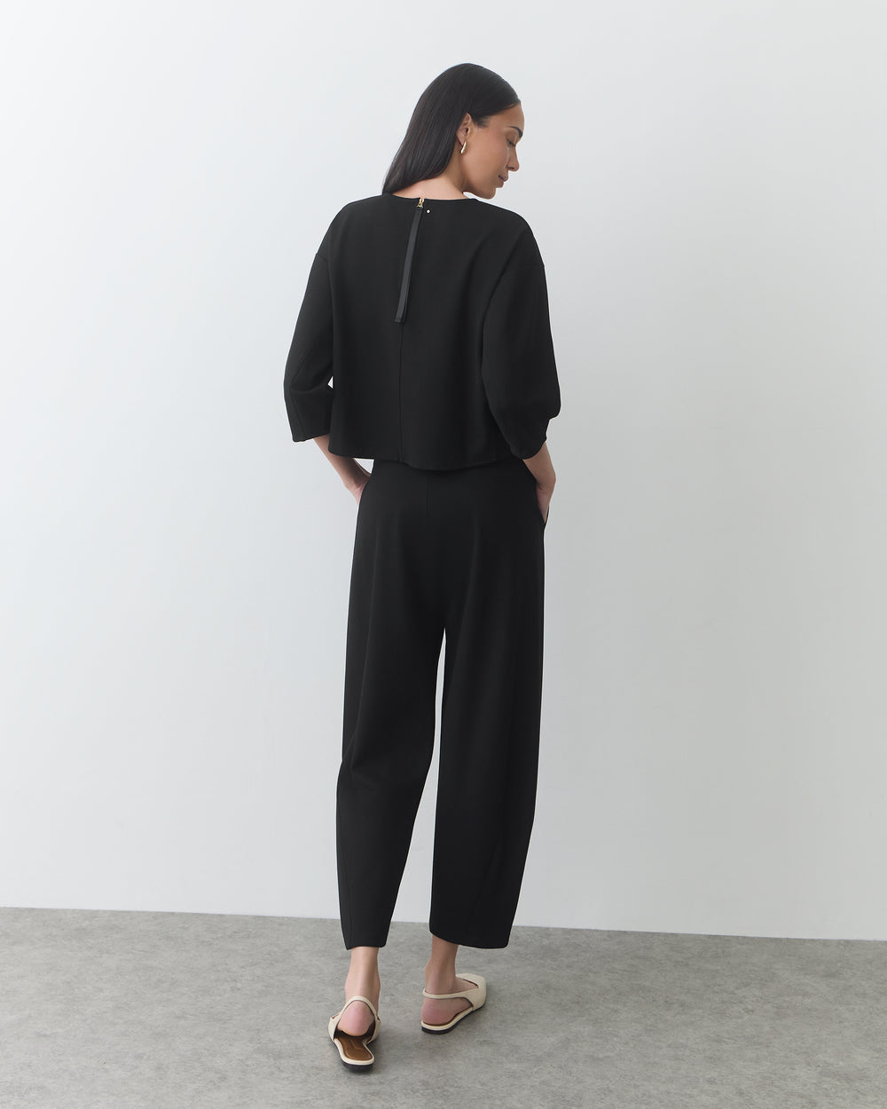 Person wearing a matching outfit and sandals, standing with their back to the camera.