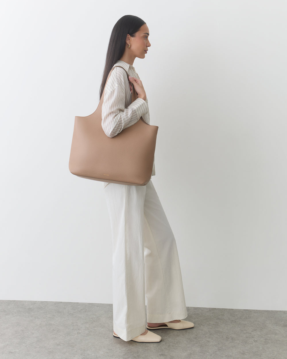 Person carrying large handbag, wearing long-sleeved top and wide pants.