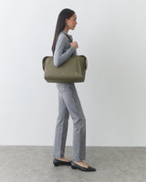 Person standing with large handbag wearing jeans and flats.