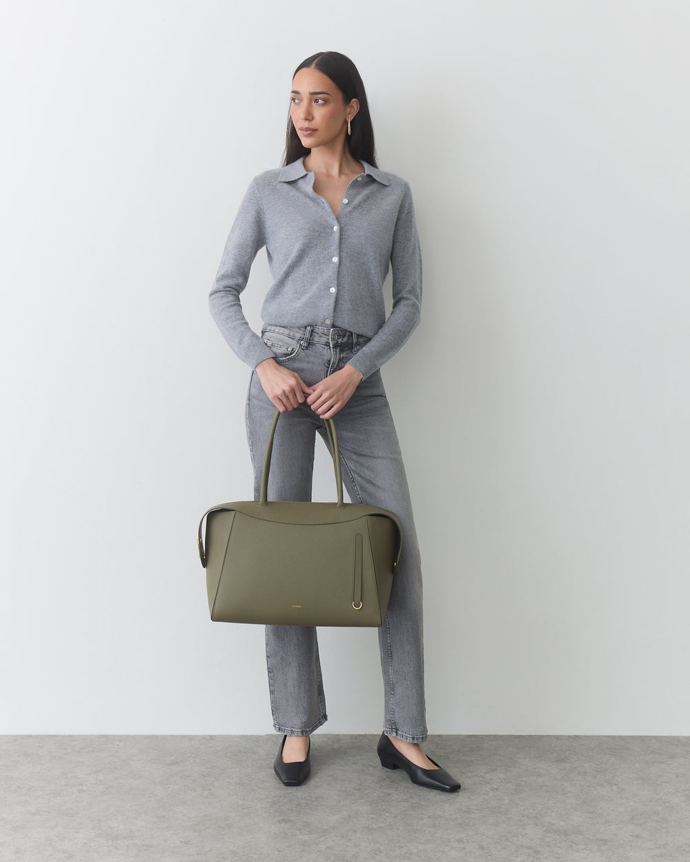 Person with travel bag wearing button-up shirt and jeans.
