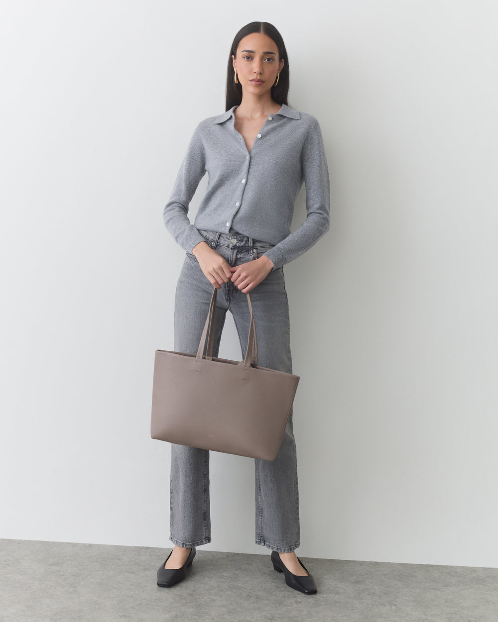 Person holding a tote bag wearing a shirt and jeans.