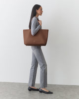 Person standing with large tote bag over shoulder.